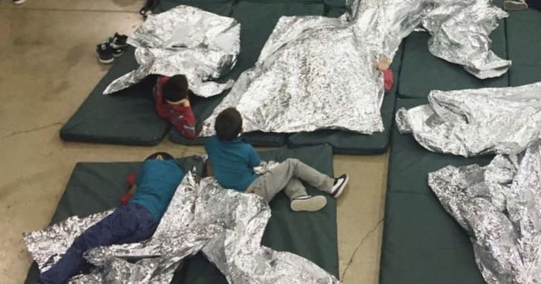 Children on the floor with space blankets in a US detention facility