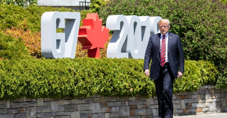 Trump walks in front of G7 sign in Montreal.