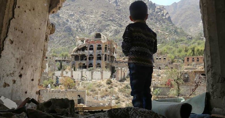 Young child looking out over bombed landscape in Yemen