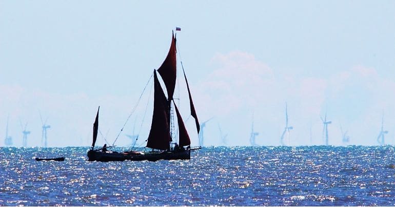 A Thames barge sailing in front of an offshore wind farm