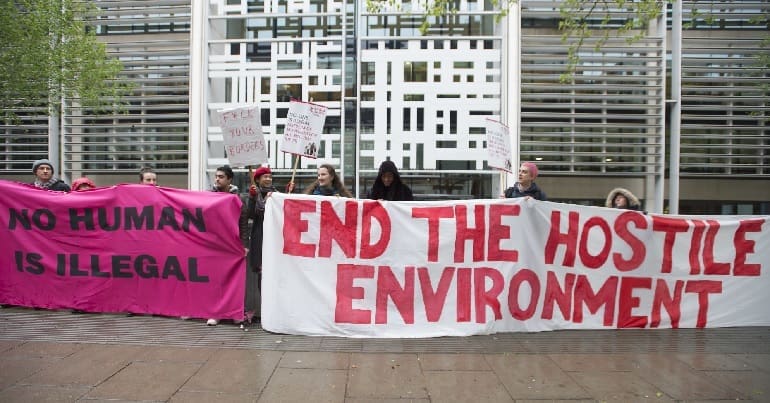 Activists holding up banners to protest against the Home Office's hostile environment policy