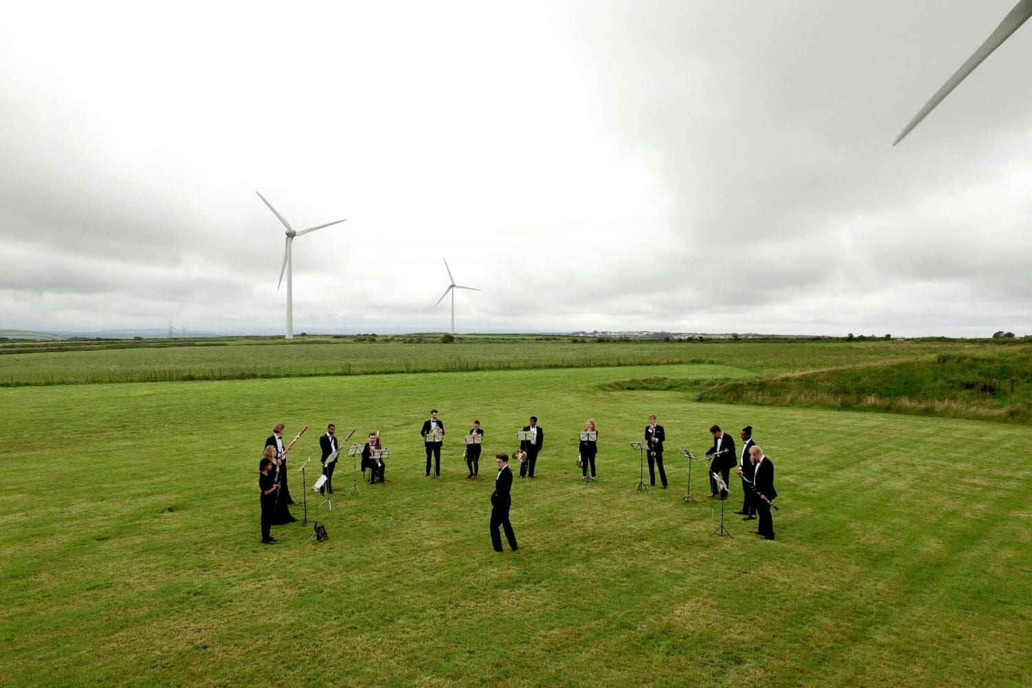 Image of a wood wind orchestra playing in a wind farm