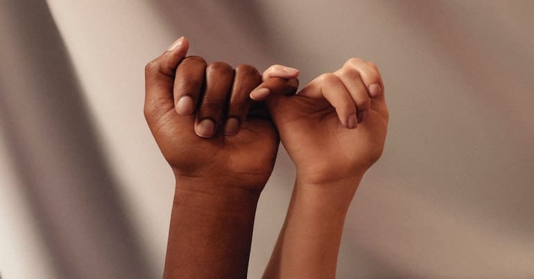 two people of colour link their hands together