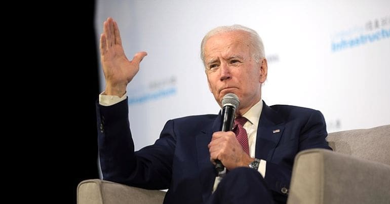 A seated Joe Biden gives a speech