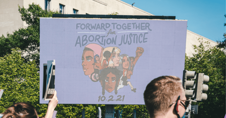 Abortion rights protestors hold up a sign saying "Forward Together - Abortion Justice"