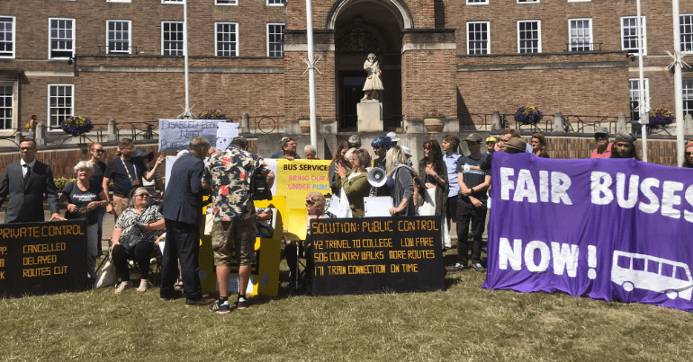 Protesters holding banners demanding 'fair buses now' in Bristol
