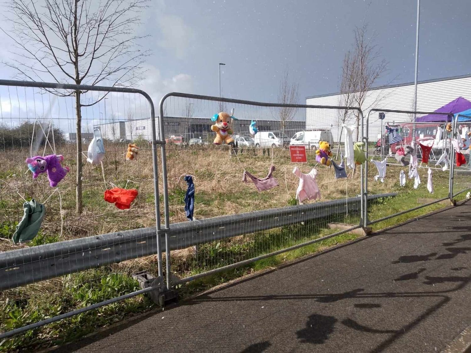 Children's toys and clothes hung on Elbit's fence in Bristol