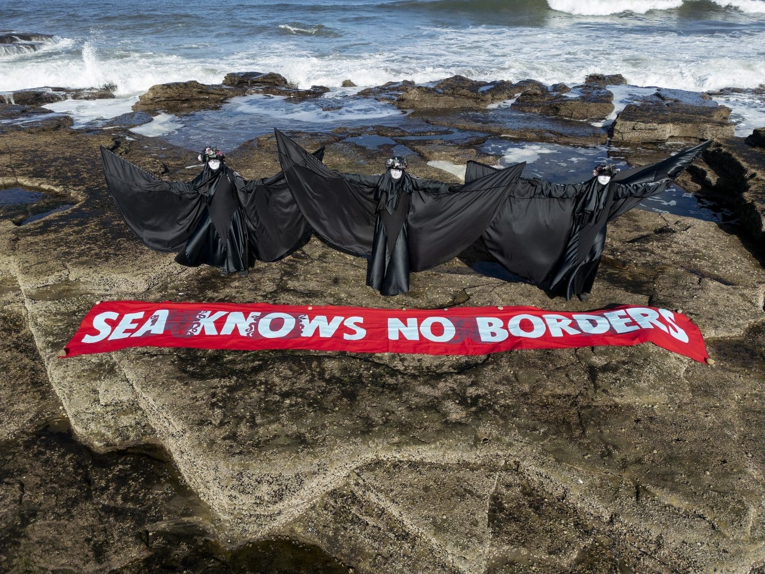 North Sea Extinction Rebellion activists on rocks with a banner that reads 'sea knows no borders'
