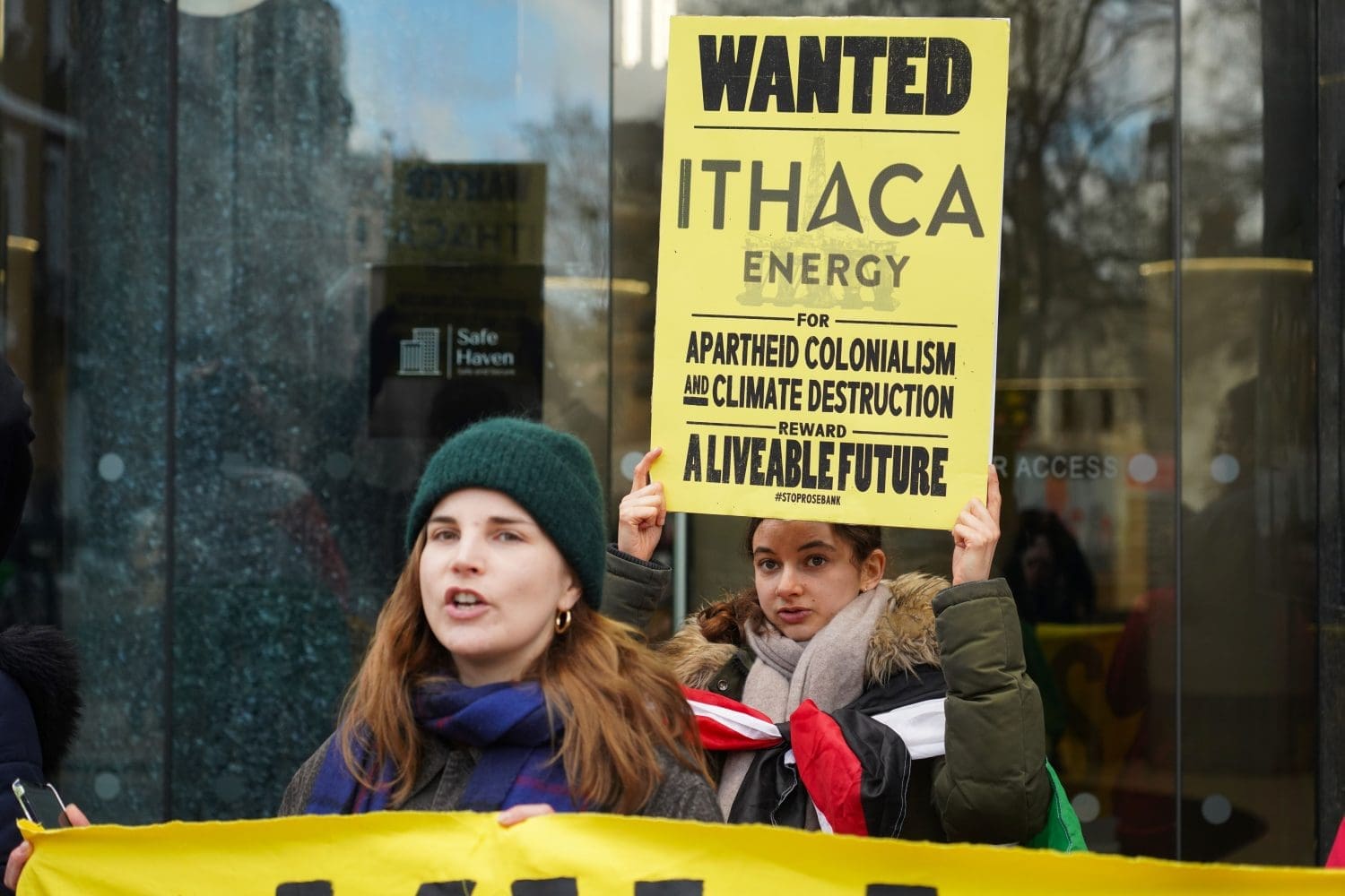 An activist raises a sign that reads: "Wanted - Ithaca Energy - for apartheid colonialism & climate destruction. Reward: a liveable future."