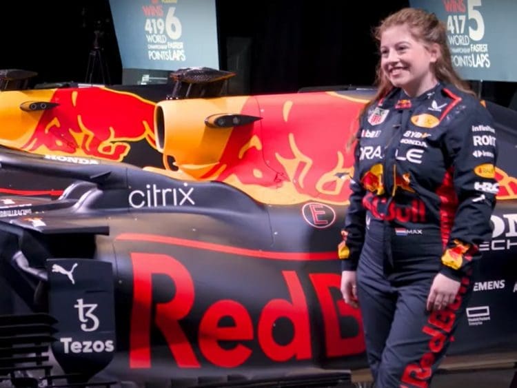 Female Red Bull Racing employee stands in front of race car.