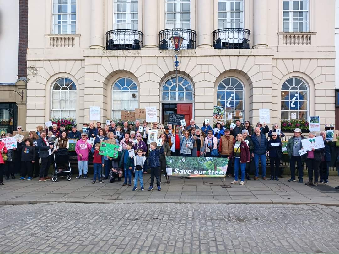 Save the Trees campaigners gather together in the city centre with placards and banners.
