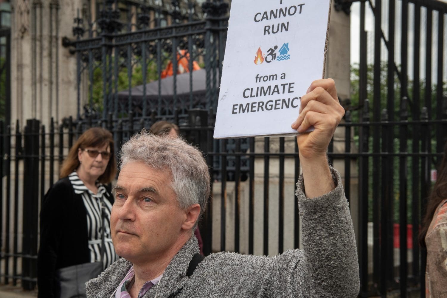 Neil Goodwin outside parliament holding up a sign that reads 'i cannot run from the climate emergency'