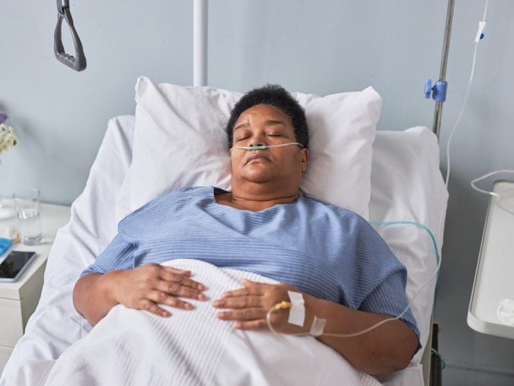 A woman with chronic illness lying in a hospital bed with ng feeding and an iv line