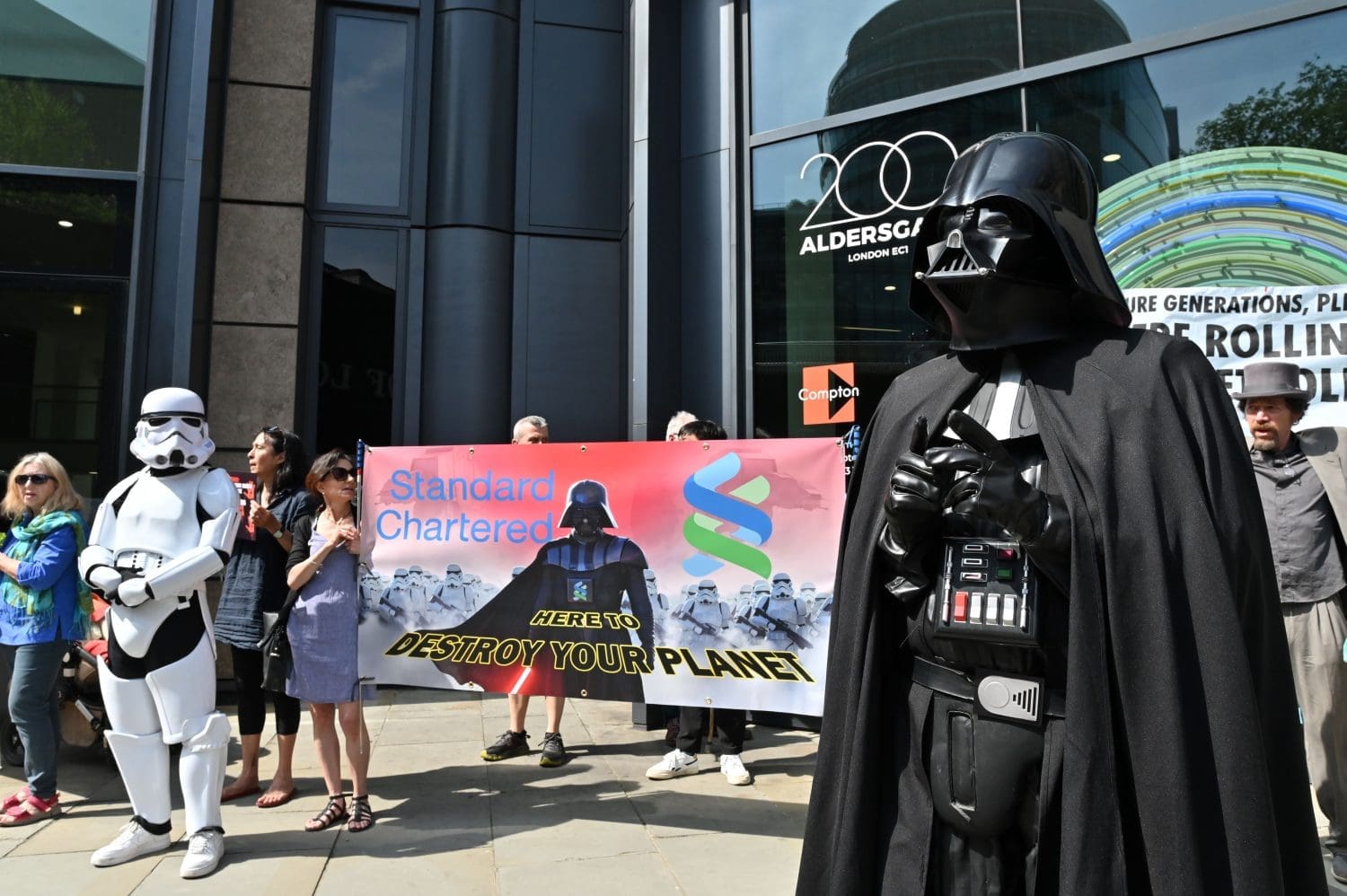 Darth Vader and a Storm Trooper alongside protesters with a banner that reads: Standard Chartered - Here to destroy your planet.