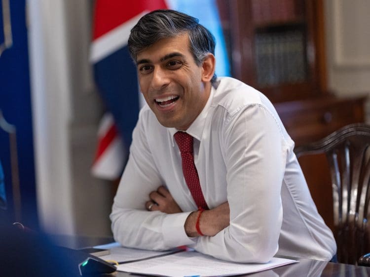 Rishi Sunak laughing at a desk with a Union Jack flag behind him DWP benefit fraud Private Eye
