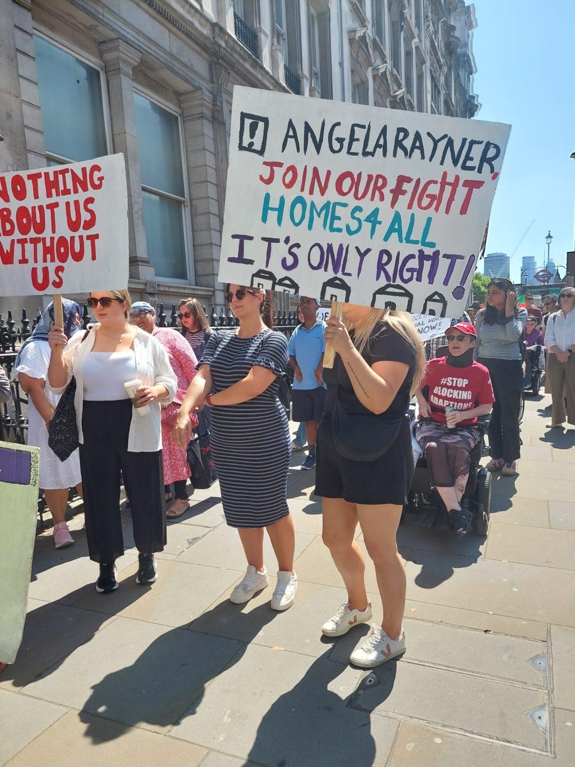 people protesting on Whitehall. One of them has a banner that reads "Angela Rayner! Join our fight" Homes 4 All it's only right" accessible housing protest