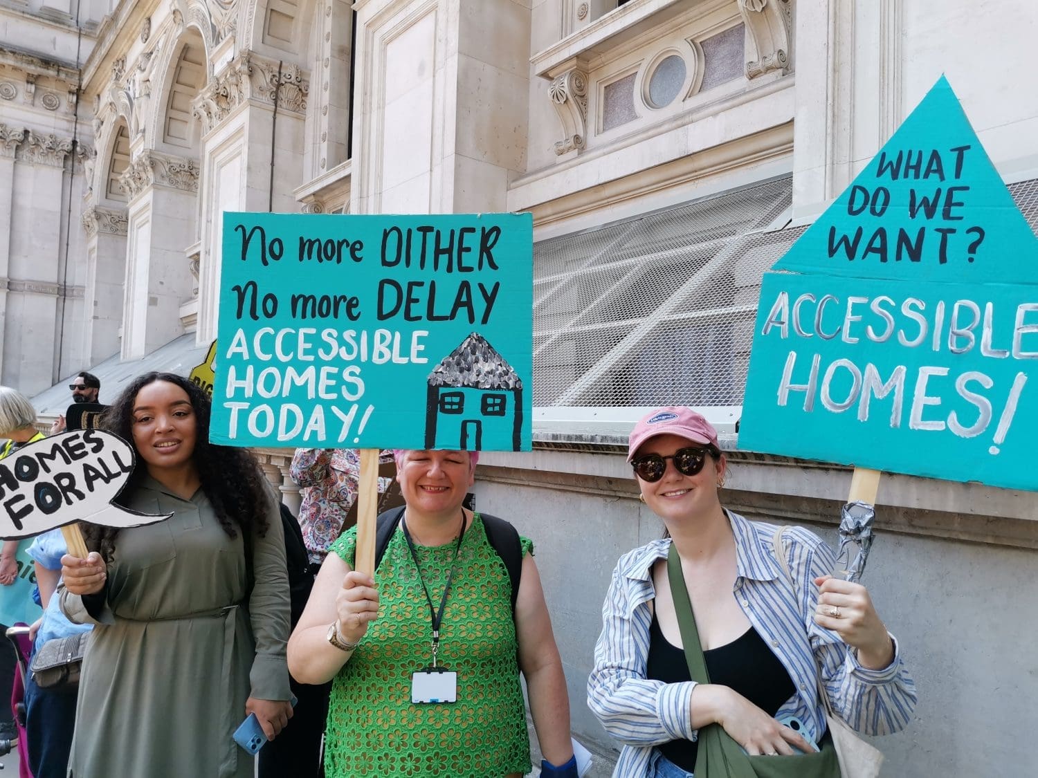 people holding banners outside whitehall that read "no more dither no more delay accessible homes today! and "what do we want? accessibly homes!"